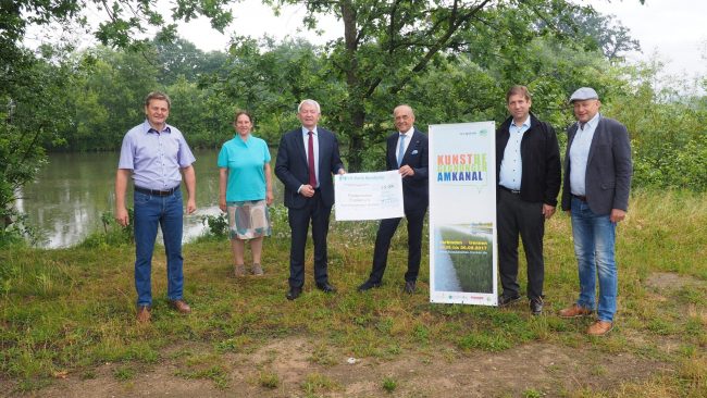 Übergabe Spendenscheck Kunstbegegnungen am Kanal. Foto: Kohn/VR Bank Bamberg-Forchheim Ganz konkret verbindet das Projekt „Kunstbegegnungen am Kanal verbinden//trennen“ die Landkreise Bamberg und Forchheim. Darum wurde für die Übergabe des Spendenschecks in Höhe von 10.000,- Euro als symbolischer Ort die Landkreisgrenze gewählt, die zwischen der Gemeinde Altendorf und dem Markt Eggolsheim verläuft. V.l.n.r: Bürgermeister Karl-Heinz Wagner (Gemeinde Altendorf), Anne Schmitt (Geschäftsführerin Flussparadies Franken e. V.), Landrat Johann Kalb (Lkr. Bamberg), Vorstandsvorsitzender