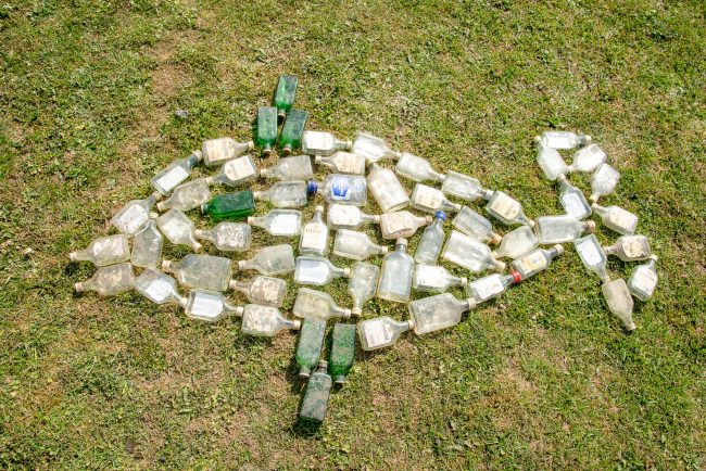 Die beim Müll-Sammeln gefundenen Glasflaschen haben die Kinder in Form eines Fisches arrangiert. Danach wandern die Flaschen in den Container fürs Recycling. Foto: Thomas Ochs Die beim Müll-Sammeln gefundenen Glasflaschen haben die Kinder in Form eines Fisches arrangiert. Danach wandern die Flaschen in den Container fürs Recycling. Foto: Thomas Ochs