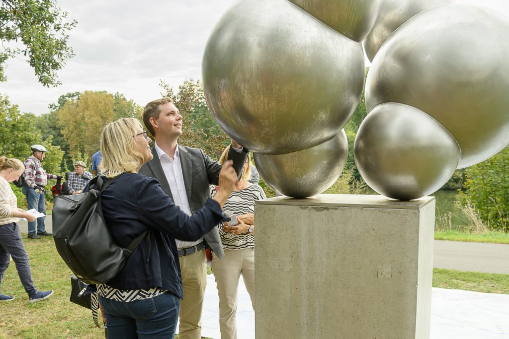 Die Nürnberger Künstlerin Michaela Biet erläutert ihr Kunstwerk, das zwei Wassermoleküle darstellt, Bambergs Bürgermeister Jonas Glüsenkamp. Foto: Thomas Ochs