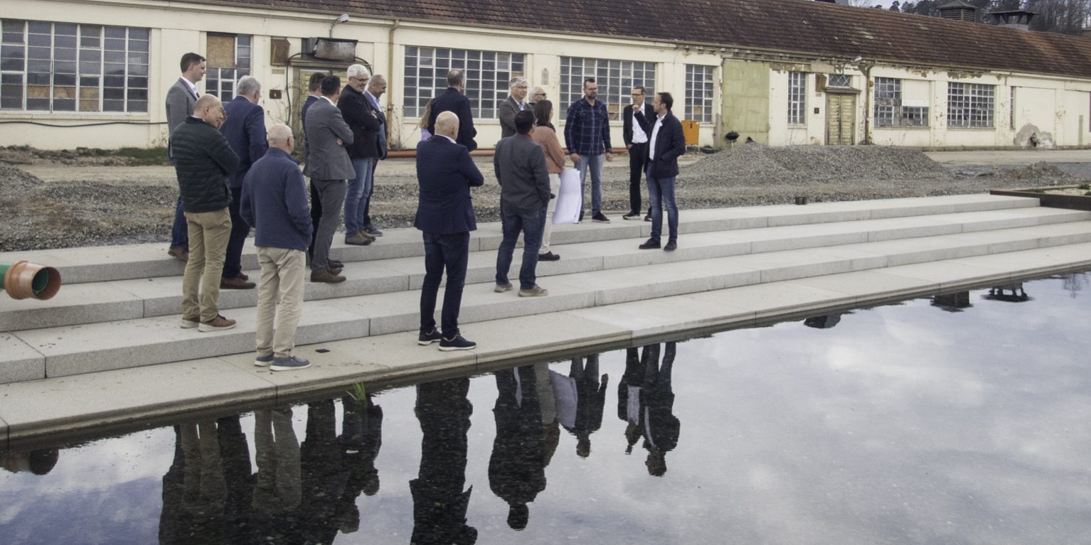 Während der Führung zeigt Bürgermeister Robert Bosch den Mitgliedern des Flussparadies Franken den auf dem Spinnereigelände neu angelegten See, welcher gleichzeitig als Regenwasserbecken dient. In dem See wird das Regenwasser des gesamten Areals aufgefangen – ein eindrucksvolles Beispiel für das Konzept der Schwammlandschaft. Foto: Flussparadies Franken e. V. Während der Führung zeigt Bürgermeister Robert Bosch den Mitgliedern des Flussparadies Franken den auf dem Spinnereigelände neu angelegten See, welcher gleichzeitig als Regenwasserbecken dient. In dem See wird das Regenwasser des gesamten Areals aufgefangen – ein eindrucksvolles Beispiel für das Konzept der Schwammlandschaft. Foto: Flussparadies Franken e. V.