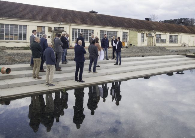 Während der Führung zeigt Bürgermeister Robert Bosch den Mitgliedern des Flussparadies Franken den auf dem Spinnereigelände neu angelegten See, welcher gleichzeitig als Regenwasserbecken dient. In dem See wird das Regenwasser des gesamten Areals aufgefangen – ein eindrucksvolles Beispiel für das Konzept der Schwammlandschaft. Foto: Flussparadies Franken e. V. Während der Führung zeigt Bürgermeister Robert Bosch den Mitgliedern des Flussparadies Franken den auf dem Spinnereigelände neu angelegten See, welcher gleichzeitig als Regenwasserbecken dient. In dem See wird das Regenwasser des gesamten Areals aufgefangen – ein eindrucksvolles Beispiel für das Konzept der Schwammlandschaft. Foto: Flussparadies Franken e. V.