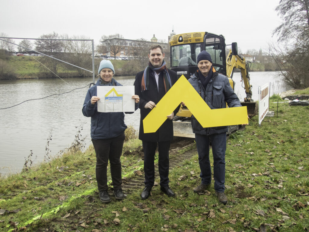Baubeginn für die neue Kanutreppe am Bamberger Faltboot-Club. Zum Saisonstart 2026 soll alles fertig sein und die Gelbe Welle die Anlegestelle vom Fluss aus gut kenntlich machen. v. l. n. r: Dr. Anne Schmitt (Geschäftsführerin Flussparadies Franken), Bürgermeister Jonas Glüsenkamp (stellv. Vorsitzender Flussparadies Franken), Ronald Schwarz (Vorstandsvorsitzender Bamberger Faltboot-Club). Foto: Flussparadies Franken