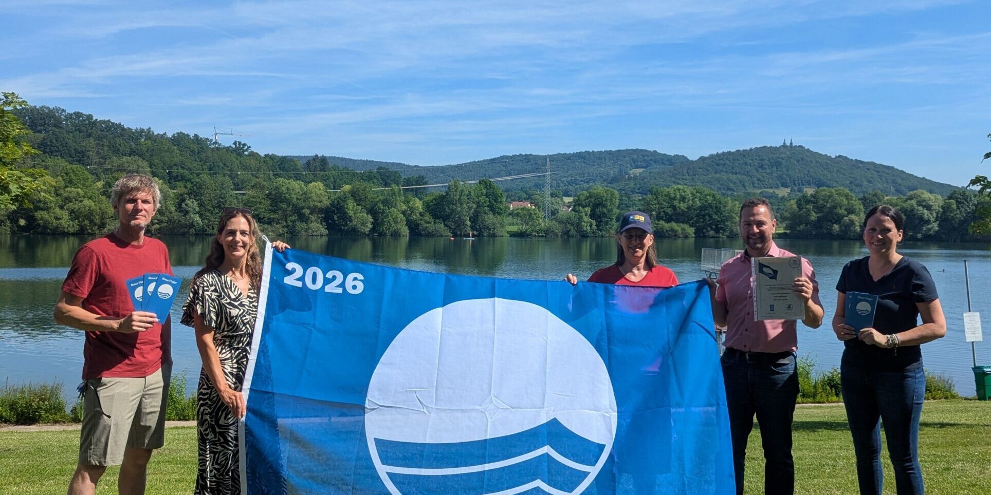 Gemeinsames Hissen der Flagge am Ostsee Bad Staffelstein (von links): Martin Lüders (Freizeit GmbH), Anne Maria Schneider (Leitung Tourist Information Bad Staffelstein), Anne Schmitt (Flussparadies Franken), Mario Schönwald (Erster Bürgermeister Stadt Bad Staffelstein), Susanne Müller (Freizeit GmbH). Foto: Tourist Information Bad Staffelstein / Carolin Böhmer Gemeinsames Hissen der Flagge am Ostsee Bad Staffelstein (von links): Martin Lüders (Freizeit GmbH), Anne Maria Schneider (Leitung Tourist Information Bad Staffelstein), Anne Schmitt (Flussparadies Franken), Mario Schönwald (Erster Bürgermeister Stadt Bad Staffelstein), Susanne Müller (Freizeit GmbH). Foto: Tourist Information Bad Staffelstein / Carolin Böhmer
